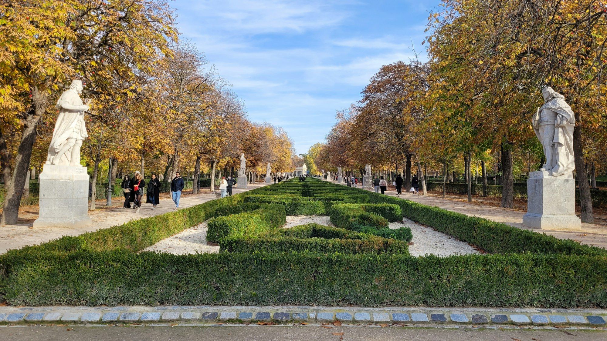 A tree-lined avenue with statues in Madrid