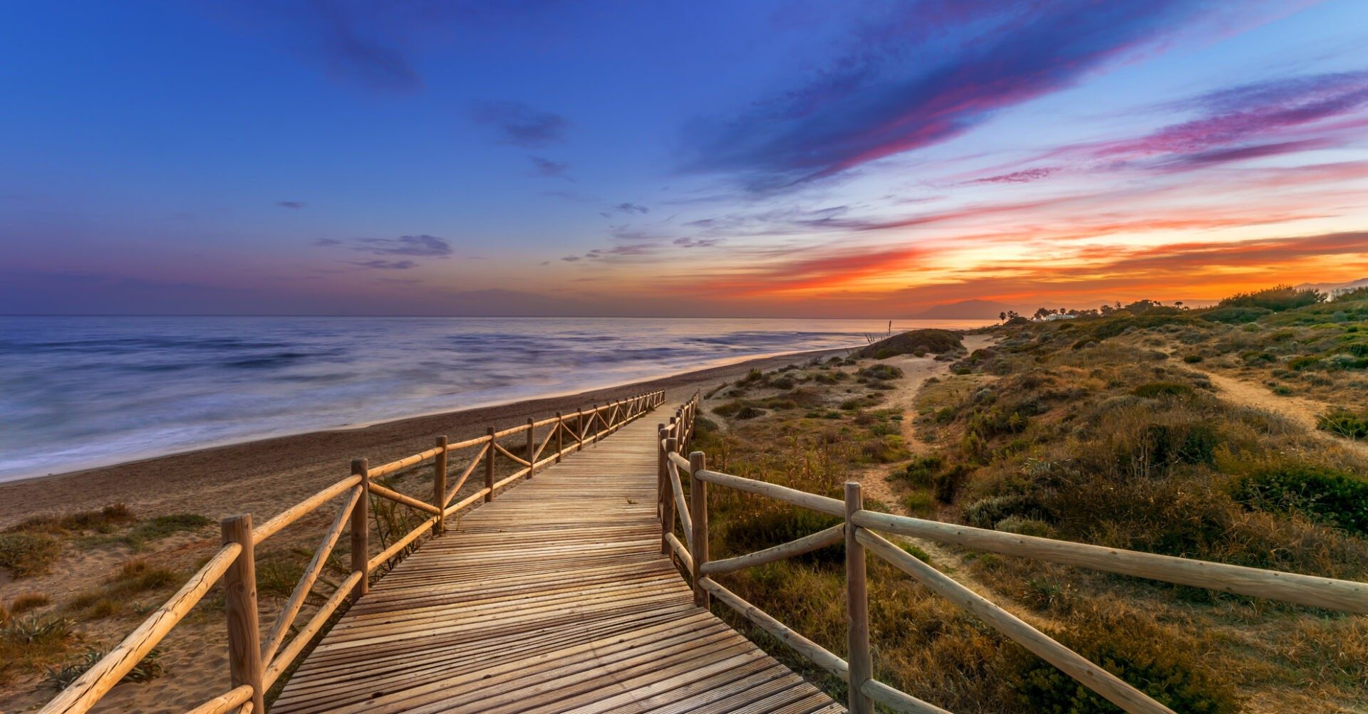 A wooden boardwalk through the dunes at sunset, east of Marbella