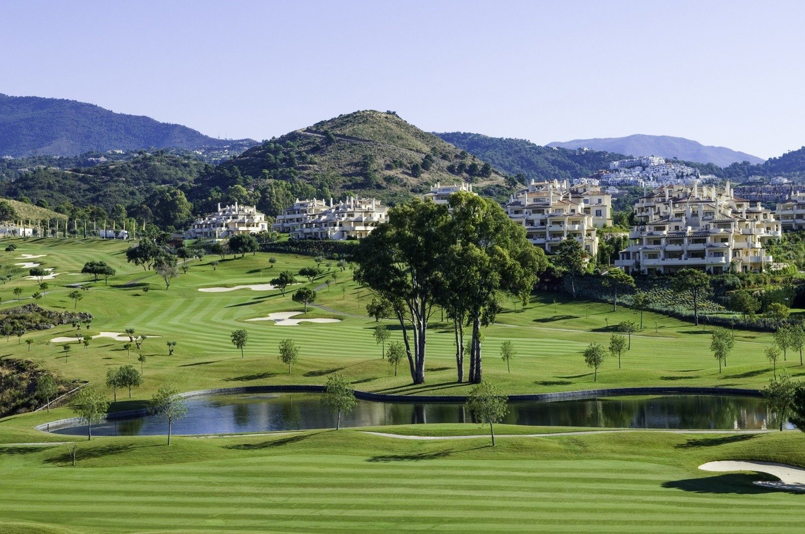 A golf course with a pond, below the hills of Benahavís
