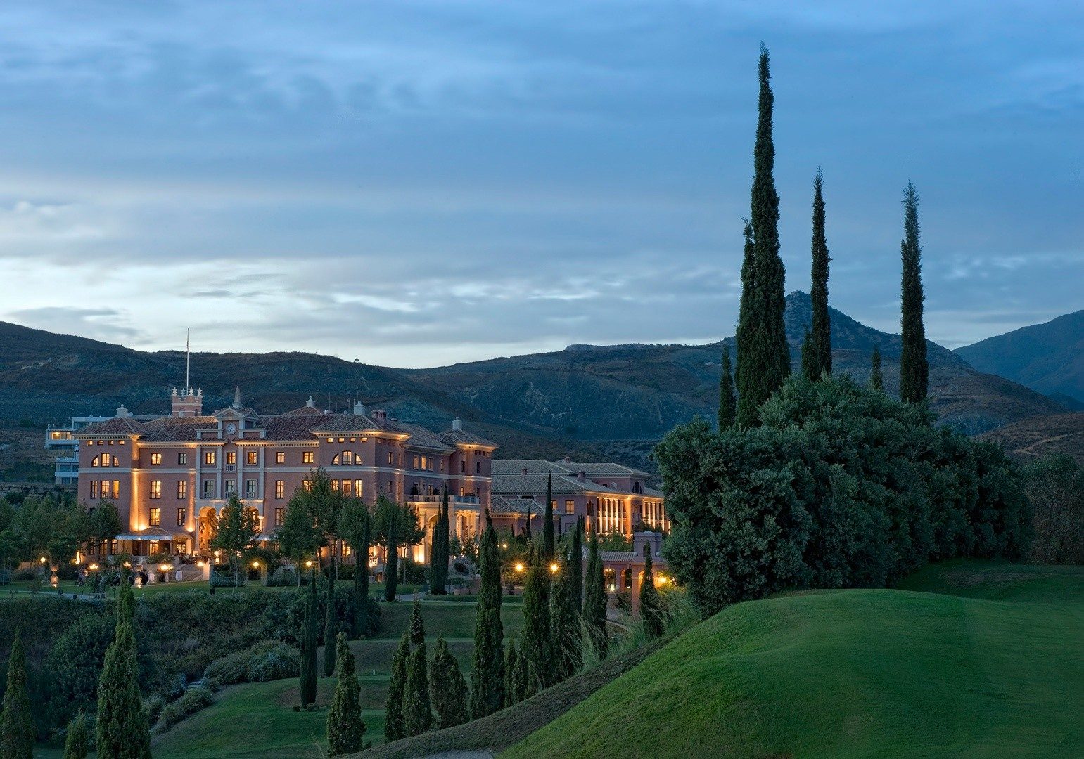 A hotel among cypress trees at dusk