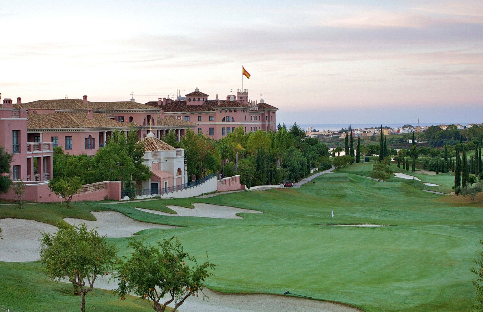 A pink hotel and golf course with the sea behind